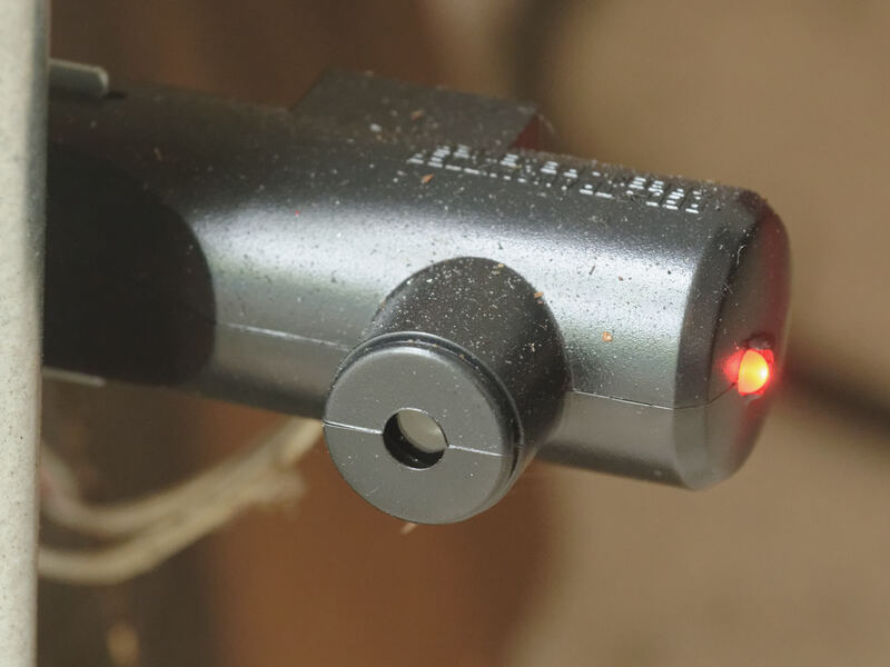 The safety sensor of an automatic garage door opener, mounted low on the door track